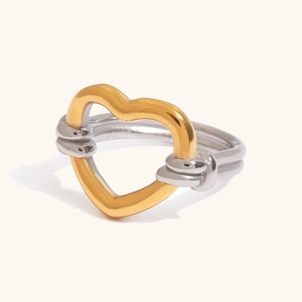 Minimalist heart-shaped gold ring with silver band and knot detail, ideal for romantic styling.

