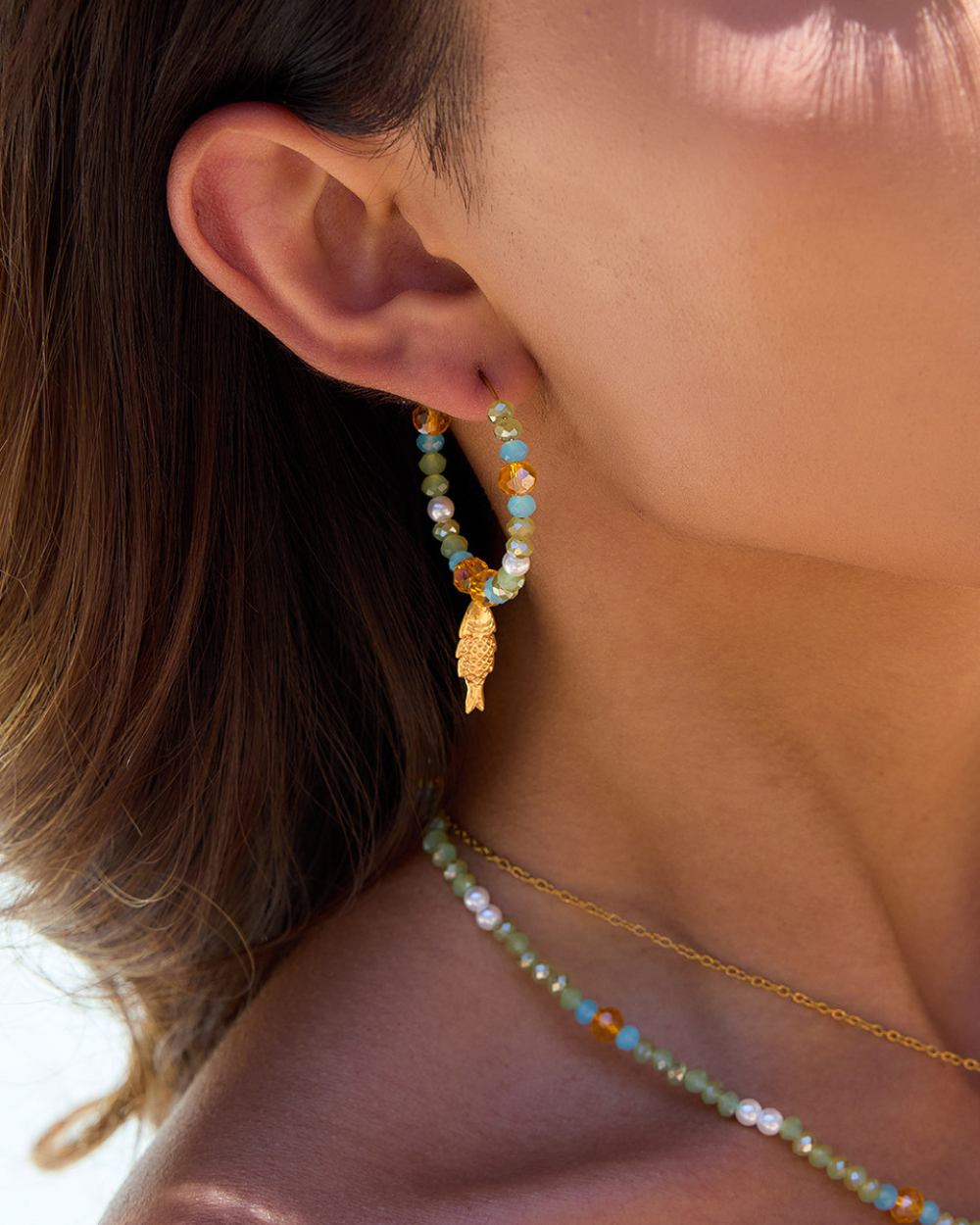 Close-up of a person wearing beaded earrings and a necklace with a blurred background