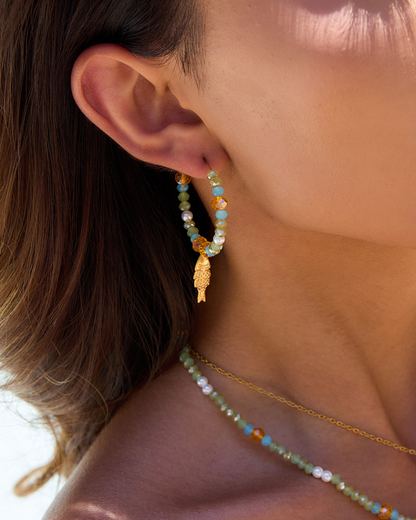 Close-up of a person wearing beaded earrings and a necklace with a blurred background