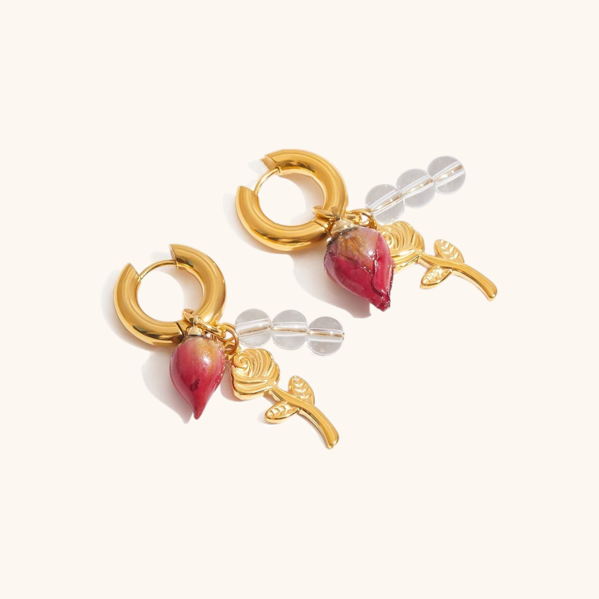 Product photo of floral earrings with gold hoops, preserved rosebud, stem and clear beads