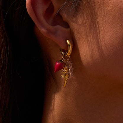Woman wearing gold hoop earrings with real rosebud, flower stem, and glass bead details