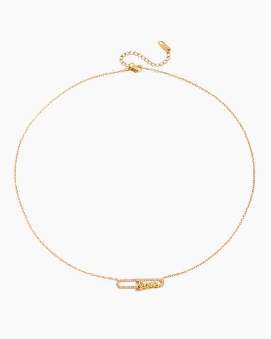 Close-up of gold chain necklace with a dainty LOVE pendant in a safety pin design, displayed on a white background.