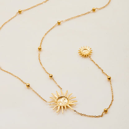 Gold necklace with sun-shaped pendants on a light beige background