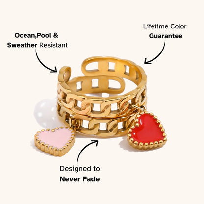 Two gold chain rings with pink and red hearts beside green grapes