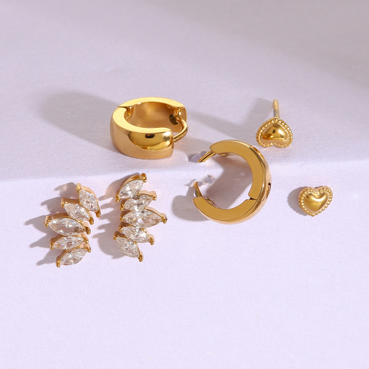 three pair gold earring set including hoops, heart studs, and crystal crawlers