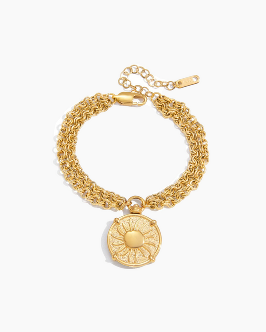 Gold bracelet with a circular pendant on a white background
