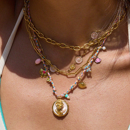 Model wearing multicolor cord necklace with gold rose pendant