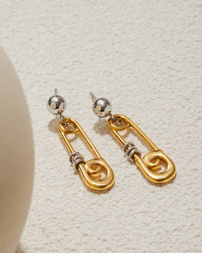 Gold and silver earring on a textured beige surface