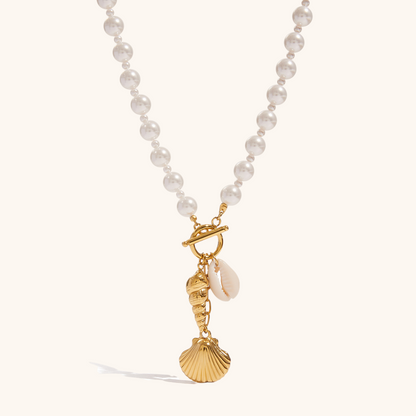 Product image of gold toggle necklace with pearl beads and ocean charms on a plain background