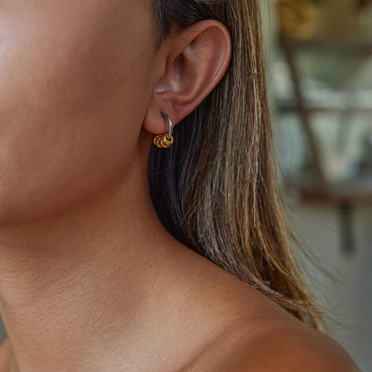 Model wearing gold and silver chunky hoop earrings, close-up ear view