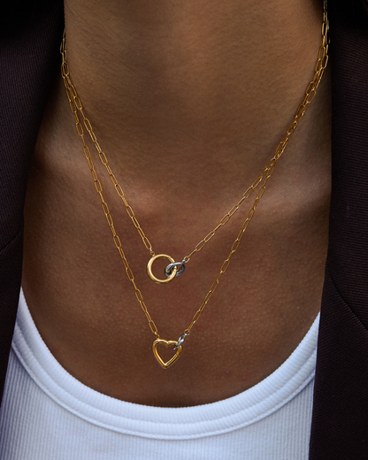 Gold necklaces with heart and moon designs on a person's neck.