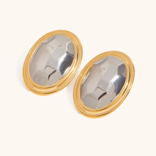Minimalist oval earrings with shiny silver center and gold border placed on neutral background