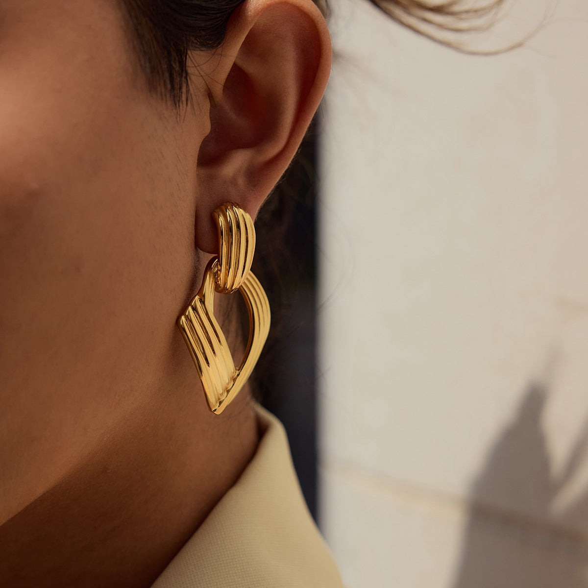 Gold vintage-style earrings worn by model in natural sunlight
