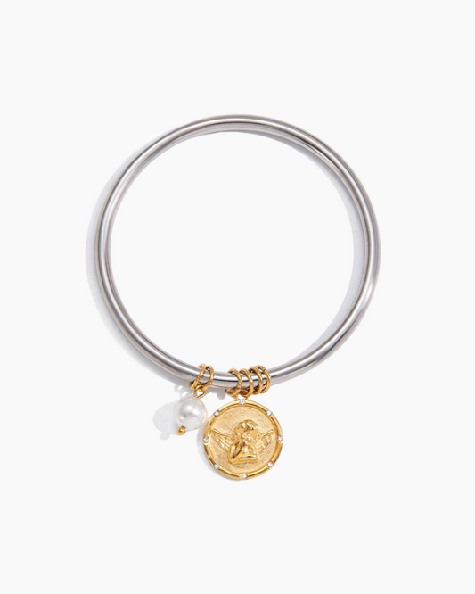 Silver bangle with gold charm and pearl on a white background