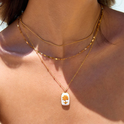 Three-layer gold necklace with autumn tree enamel pendant on model under sunlight