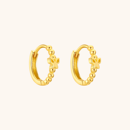 Close-up of gold butterfly hoop earrings on white background, featuring a delicate beaded design.