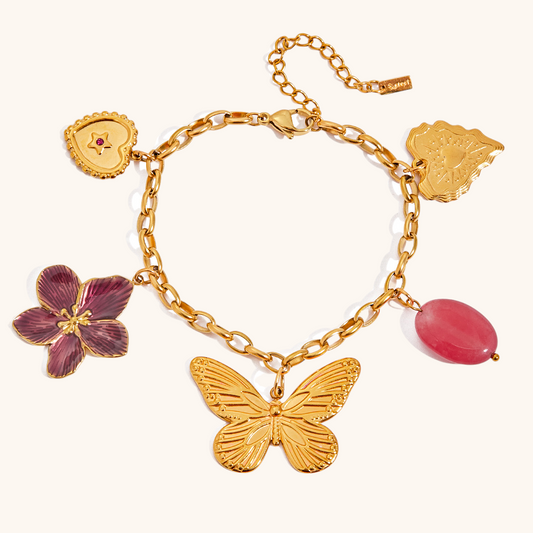 Close-up of gold link bracelet with heart, flower, and butterfly charms