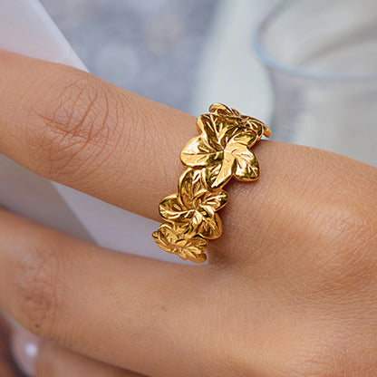Golden Bloom Ring worn on index finger with glossy gold finish and raised cherry blossom motif