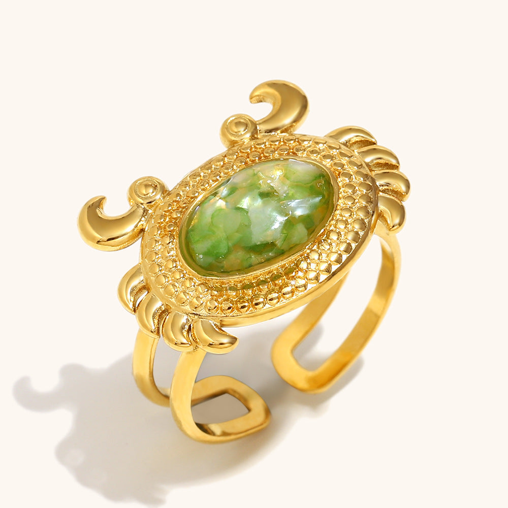 Gold crab-shaped ring with vibrant green shell inlay and textured claws.