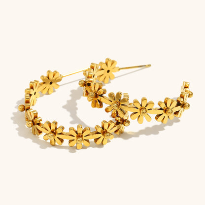 gold-plated daisy hoop earrings styled next to a ceramic object under natural light, casting floral shadows