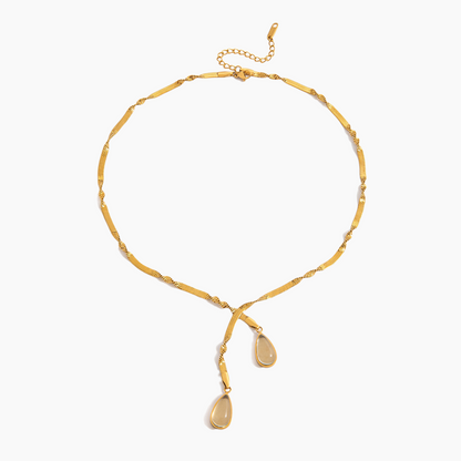 Gold necklace with teardrop pendants on a white background
