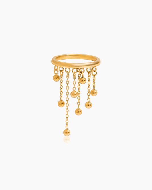 Gold ring with dangling beads on a white background