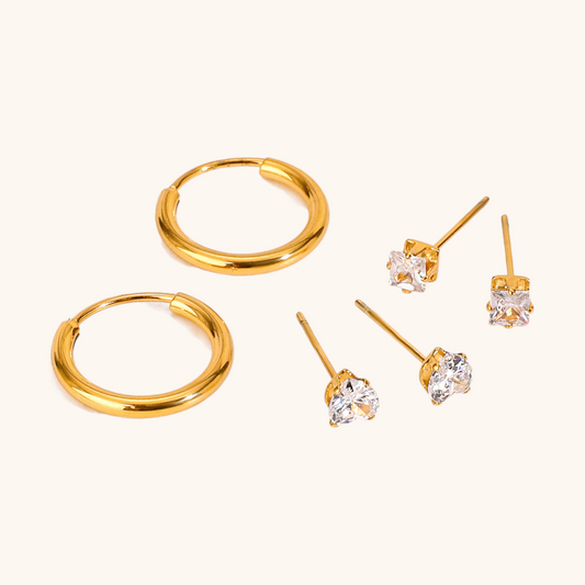 Close-up of shiny gold hoops and brilliant-cut crystal studs on soft beige background