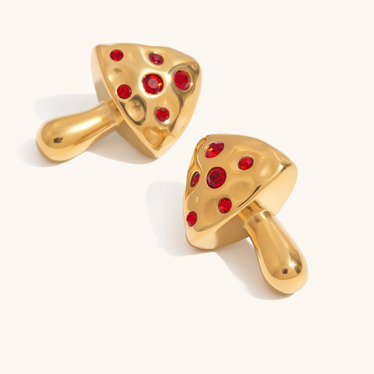 Gold mushroom earrings with red crystals on ear, close-up shot
