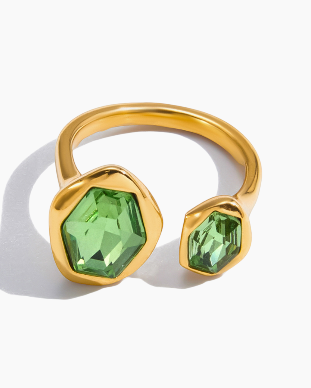 Gold ring with green gemstones on a white background