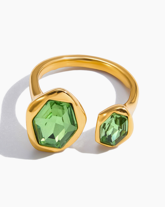 Gold ring with green gemstones on a white background