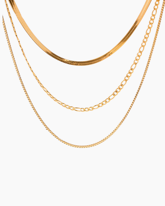 Three gold chains of different styles on a white background