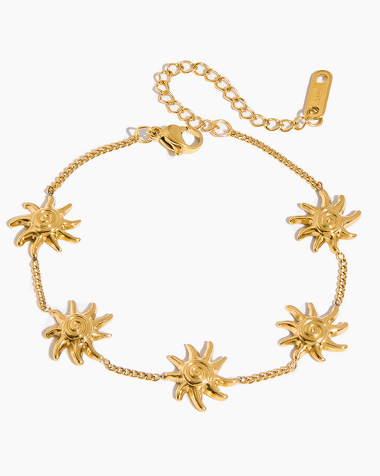 Gold bracelet with sun-shaped charms on a white background