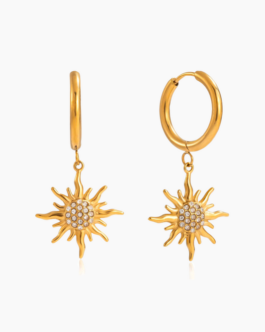 Gold hoop earrings with sun-shaped charms on a white background