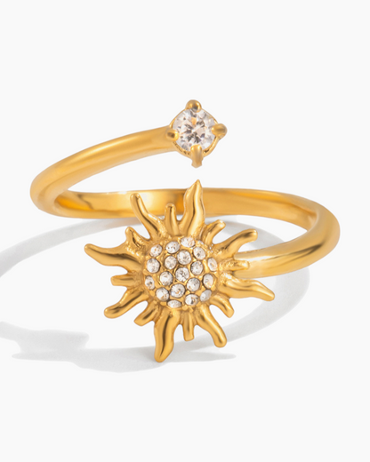 Gold ring with sun design and small gemstone on a white background