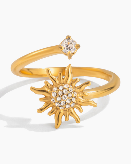 Gold ring with sun design and small gemstone on a white background