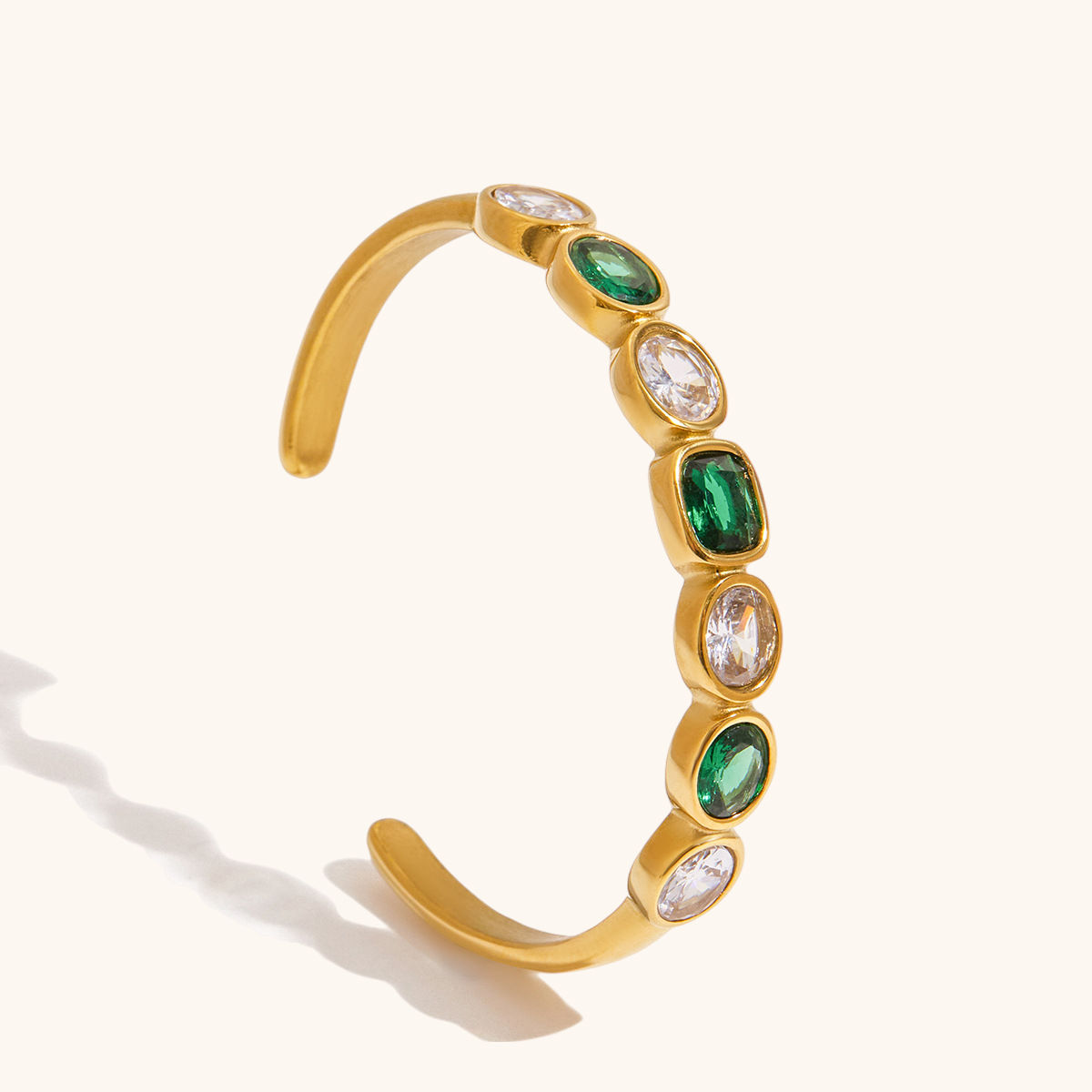 Elegant green gemstone bracelet on beige backdrop with textured rock.