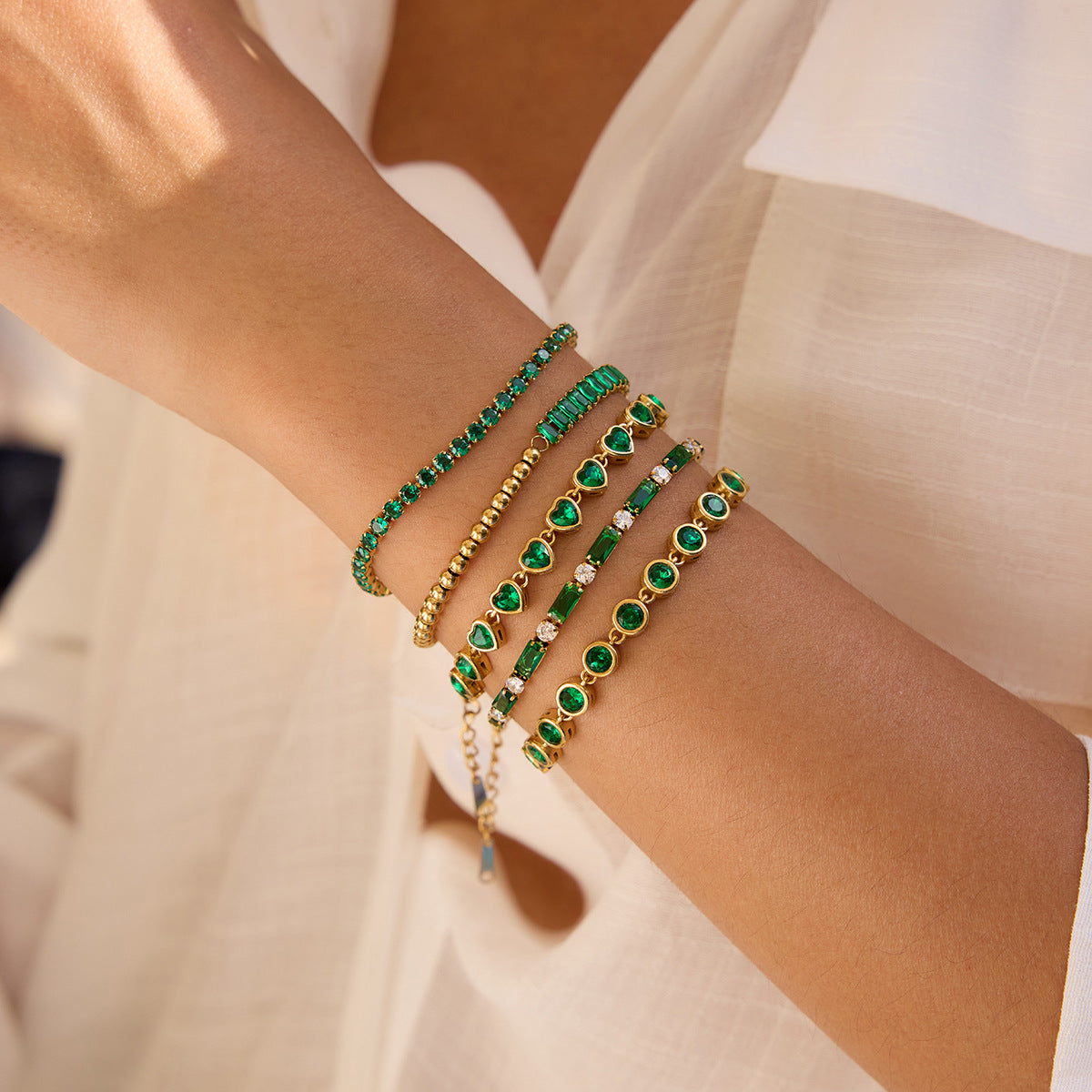 Green crystal tennis bracelet styled on wrist with white linen dress outdoors_MiFJewelry