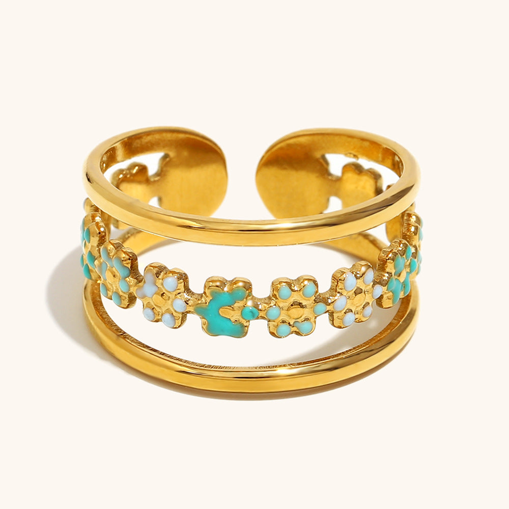 Close-up of Green and white floral enamel ring on gold base, summer jewelry style.