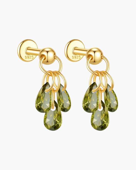 Gold earrings with green gemstones on a white background