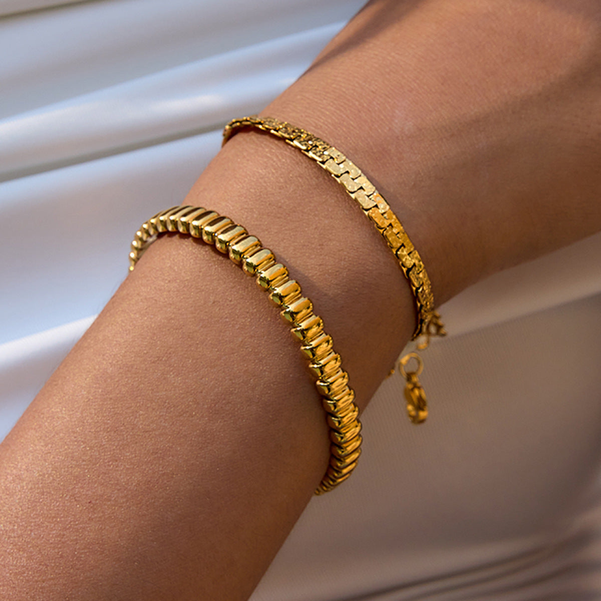 Gold hammered bracelet styled on wrist with white dress