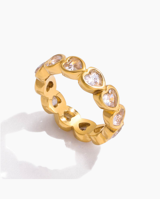 Gold ring with heart-shaped gemstones on a white background