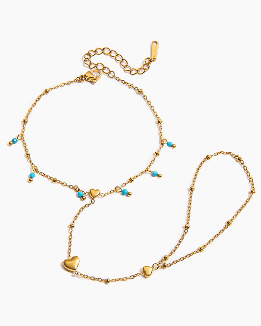 Gold anklets with heart and turquoise bead details on a white background