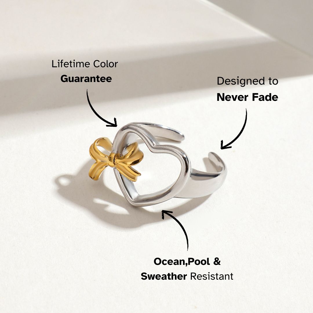 Gold and silver heart-shaped open ring with a bow on white background