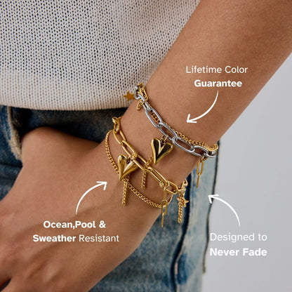 Model wearing layered heart bracelets with denim and knit top