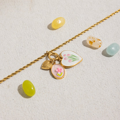 Gold necklace with multiple enamel charms laid out with candy-inspired props