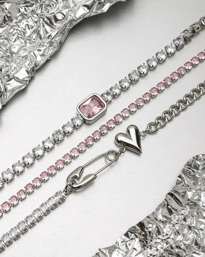 Trio of bracelets with silver heart, pink stones, and square crystal stacked for summer outfit.