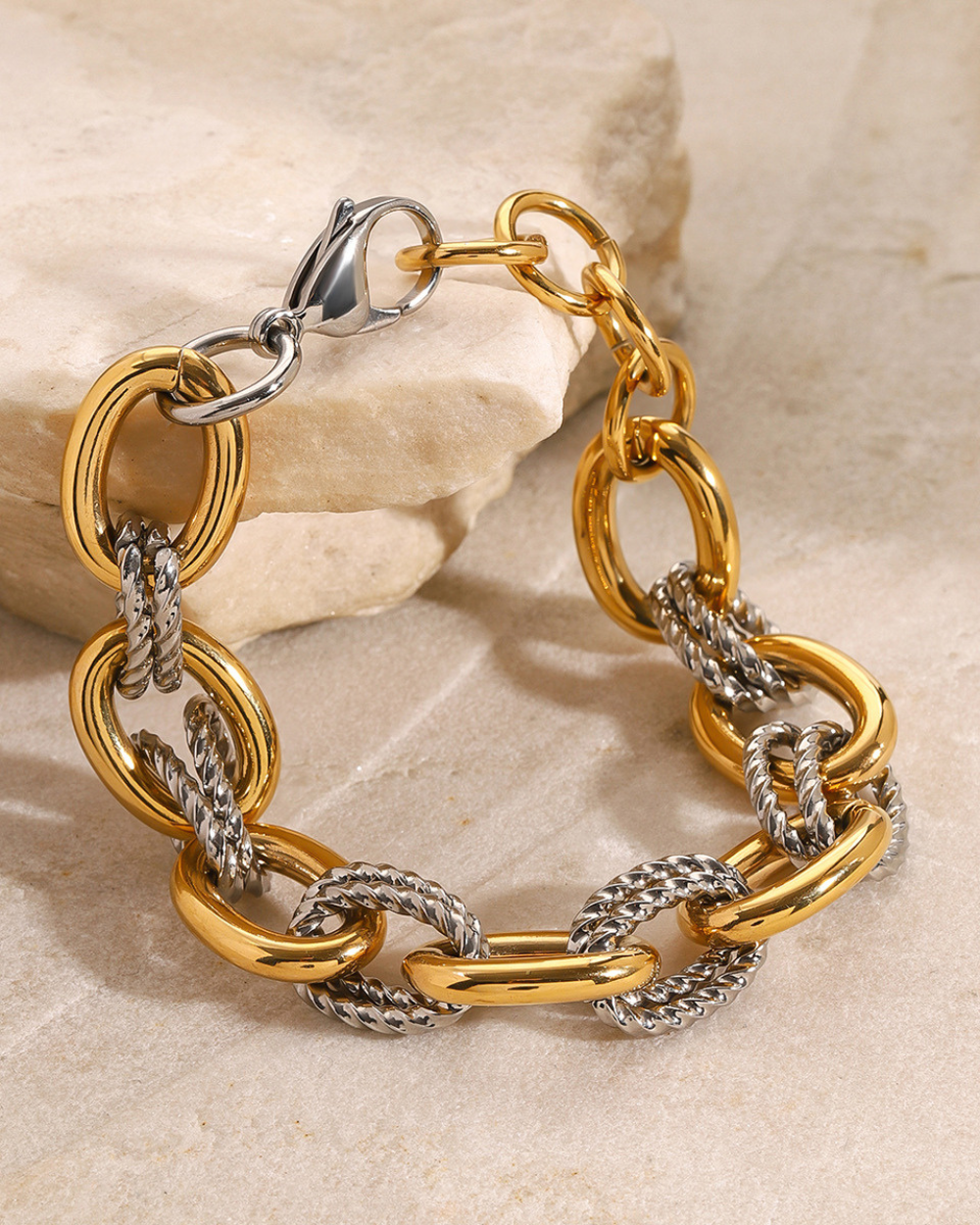 Gold and silver chain bracelet on a stone surface