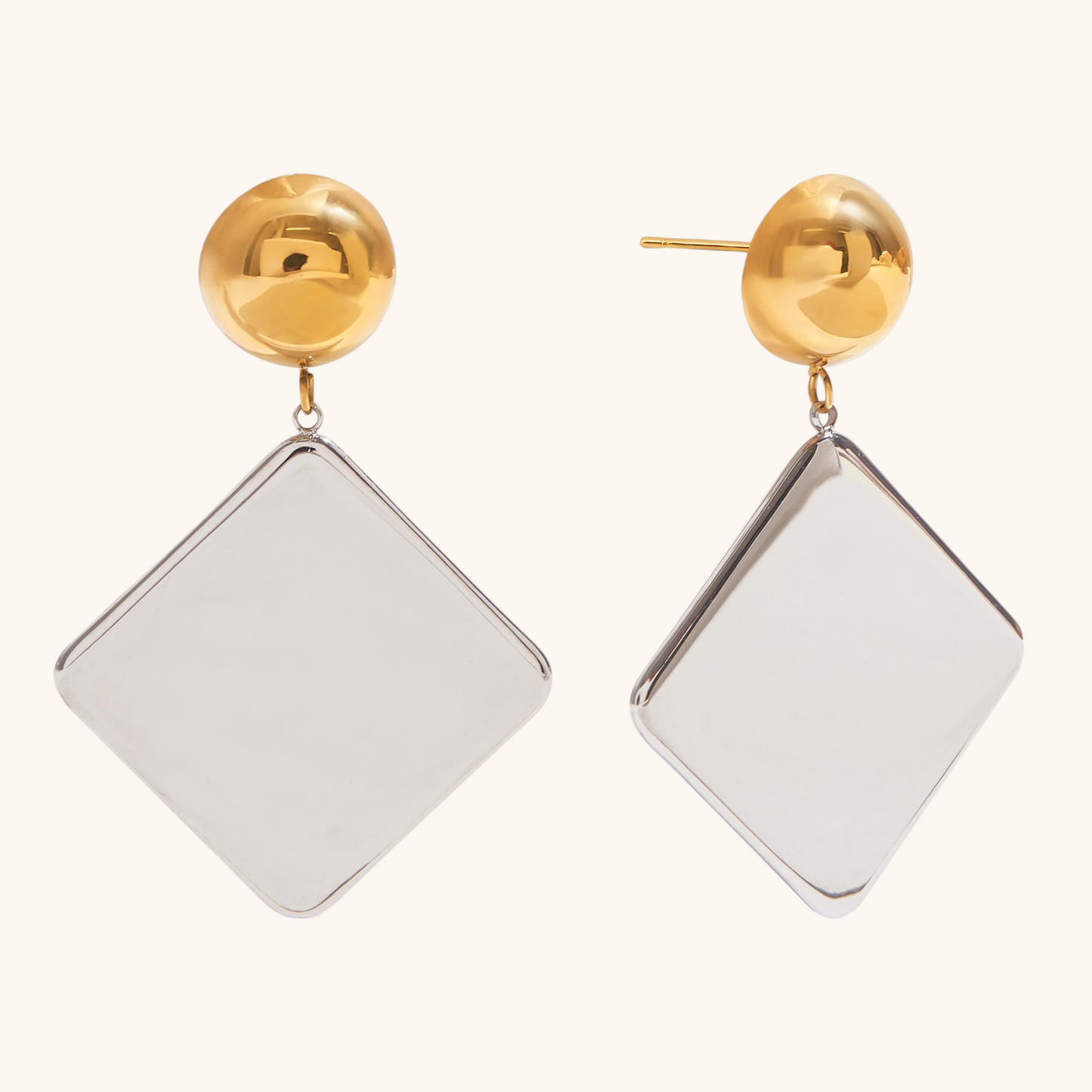 Close-up of geometric dangle earrings in silver and gold