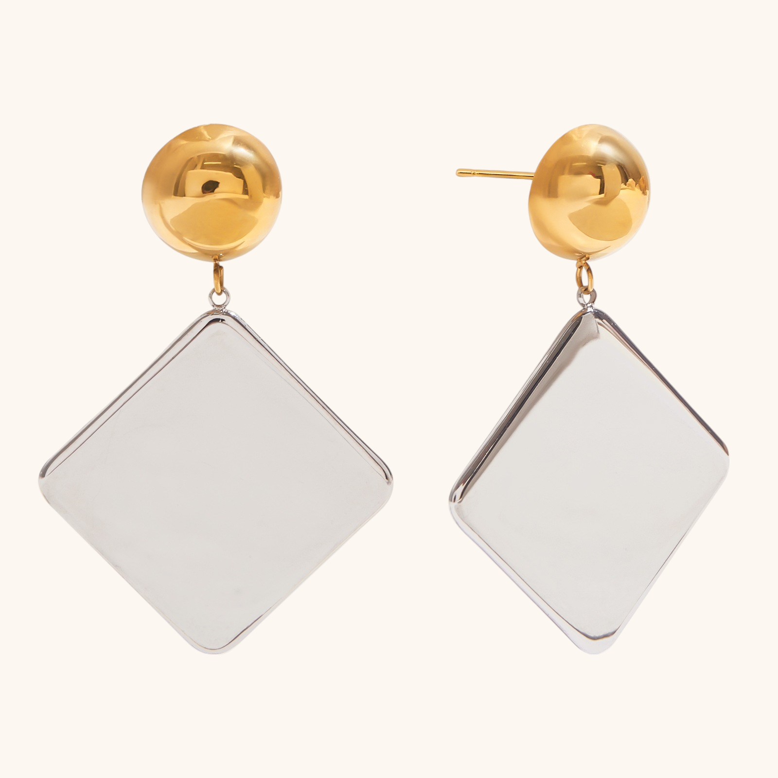 Close-up of geometric dangle earrings in silver and gold