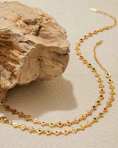 Gold necklace with colored beads on a textured beige surface